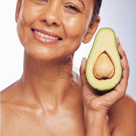 Photo for Skincare, face and mature woman with avocado in studio isolated on a white background. Portrait, natural fruit and happy model with food for organic nutrition, healthy diet and omega 3 for anti aging. - Royalty Free Image