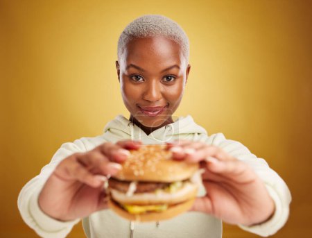 Téléchargez les photos : Burger, offre et portrait de femme ou d'étudiant sur fond jaune studio dans la promotion ou l'affaire du restaurant. Donner, manger et jeune personne africaine pour l'expérience client avec la restauration rapide ou hamburger. - en image libre de droit