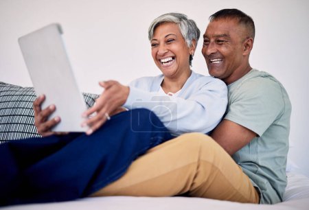 Téléchargez les photos : Lit, tablette et heureux couple de personnes âgées riant de blog drôle de réseau social, e-mail ou regarder la vidéo de comédie, podcast ou mème. Drôle d'article du matin, chambre à coucher à la maison et les personnes âgées rient, lien et câlin. - en image libre de droit