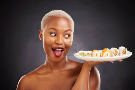 Photo for Face, surprise and woman with sushi plate in studio for healthy eating, beauty or food. Excited black female model with makeup on dark background for wellness glow, wow diet or seafood advertising. - Royalty Free Image