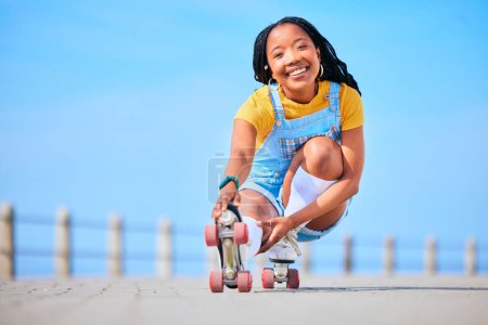 Foto de Retrato, patinaje sobre ruedas y equilibrio con una mujer negra junto al mar, en el paseo marítimo para el entrenamiento o la recreación. Playa, deporte y sonrisa con un adolescente feliz en patines en la costa junto al océano. - Imagen libre de derechos