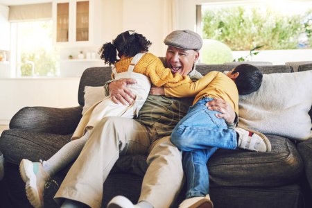 Foto de Abrazo, abuelo jugando o niños felices en el hogar familiar en el sofá con amor disfrutando de la unión de tiempo juntos. Sonrisa, afecto o abuelo mayor relajándose con niños pequeños hermanos en el sofá en casa. - Imagen libre de derechos
