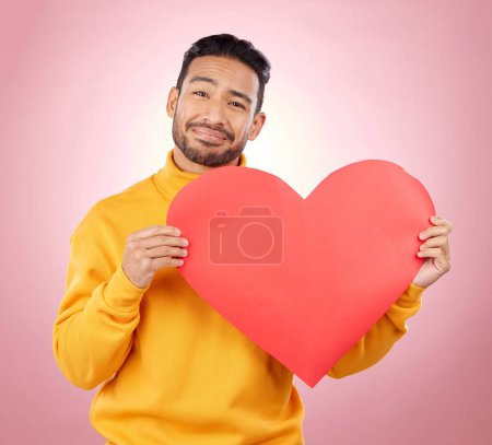 Photo for Heart, happy and love with portrait of man in studio for romance, date and valentines day. Kindness, support and hope with person and sign on pink background for wellness, peace and creative mockup. - Royalty Free Image