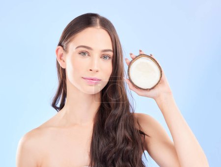 Photo for Hair, coconut oil and beauty, woman and cosmetic care with natural treatment on blue background. Female model, haircare and portrait, eco friendly fruit product for growth and shine in a studio. - Royalty Free Image