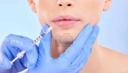 Photo for Injection, woman and lips with plastic surgeon for beauty with botox or hands in studio with blue background. Face, syringe and doctor for injecting mouth with collagen or filler and implants - Royalty Free Image