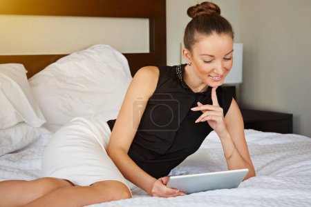 Photo for Spending some time online. Shot of a young woman using a digital tablet in her room - Royalty Free Image