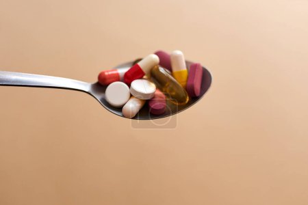 Photo for When a diet turns into an eating disorder. Studio shot of medication served in a spoon against a brown background - Royalty Free Image