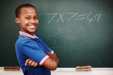 Photo for Im getting the hang of this. A proud young schoolboy standing with his arms crossed after doing a sum correctly at the blackboard - Royalty Free Image
