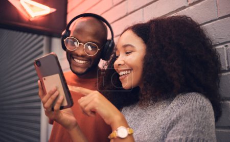 Photo for Phone, music and headphones with a multicultural couple outdoor in a city together for dating. Love, mobile or streaming app with a man and woman bonding in an urban town while listening to the radio. - Royalty Free Image