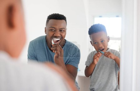 Téléchargez les photos : Homme noir se brossant les dents avec son enfant pour l'hygiène dentaire, la santé et le bien-être dans la salle de bain. Soins buccodentaires, enseignement et jeune père africain faisant la routine buccale matinale avec son enfant garçon à la maison - en image libre de droit