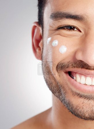Photo for Closeup, portrait and man with skincare, cream and dermatology against grey studio background. Face, male person and model with lotion, creme and grooming routine with a smile, beauty and smooth skin. - Royalty Free Image