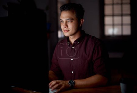 Photo for Wrapping up some deadlines. Shot of a young businessman working on a computer in an office at night - Royalty Free Image