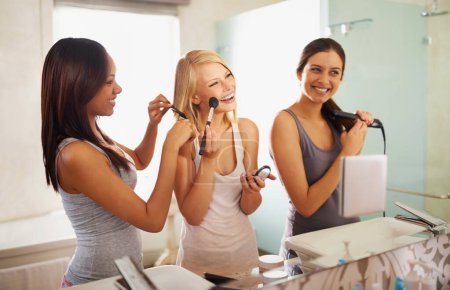 Foto de En la estación de belleza. Tiro de tres amigos aplicando maquillaje delante del espejo - Imagen libre de derechos