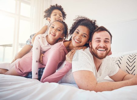 Photo for Happy family, portrait and relax on a bed, bond and having fun on the weekend in their home together. Interracial, love and face of playful children with parents in a bedroom, smile and playing games. - Royalty Free Image