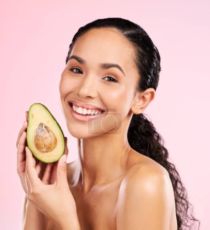 Photo for Beauty, avocado and face of a happy woman with skin care, dermatology and natural glow. Portrait of female aesthetic model with fruit for moisturizer, cosmetics or diet nutrition on a pink background. - Royalty Free Image