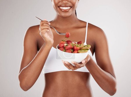 Téléchargez les photos : Femme, mains et alimentation avec salade de fruits pour une nutrition naturelle sur fond de studio blanc. Gros plan de la femme tenant bol de fraise biologique et kiwi pour perdre du poids ou un bien-être sain. - en image libre de droit