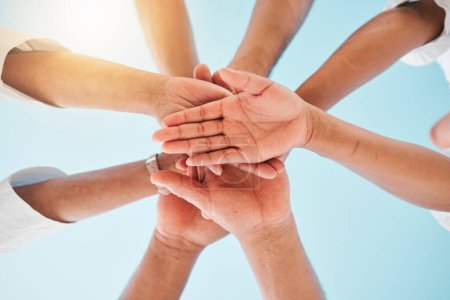 Photo for Circle, low angle and team with hands together for collaboration, unity or support by a blue sky. Teamwork, diversity and group of people in an outdoor huddle for motivation, solidarity or community - Royalty Free Image