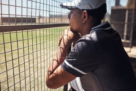 Foto de Nada lo hipnotiza como el béisbol. Tiro de un joven mirando un partido de béisbol detrás de la valla - Imagen libre de derechos