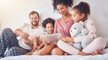 Photo for Happy family, bed and tablet streaming, movies or games while bonding, relax and play in their home. Online, subscription and children with parents in a bedroom for entertainment, fun and watching. - Royalty Free Image