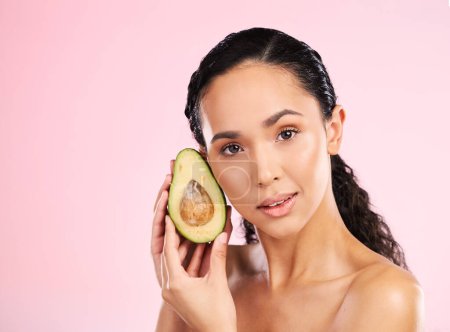 Photo for Face, skincare and serious woman with avocado in studio isolated on pink background mockup space. Portrait, natural cosmetic and model with fruit, food or nutrition for diet, vegan health or omega 3. - Royalty Free Image