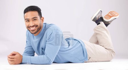 Photo for Fashion, portrait and happy man on the floor in studio isolated on a white background. Style, smile and Asian person from Cambodia in casual clothes, trendy aesthetic or confidence to relax on ground. - Royalty Free Image