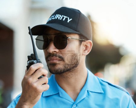Security guard, safety officer or man with a walkie talkie outdoor on a city road for communication. Serious face of person with a radio on urban street to report crime, investigation or surveillance.
