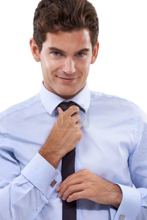 Téléchargez les photos : Habillé pour réussir. Un beau jeune homme d'affaires ajustant sa cravate - en image libre de droit