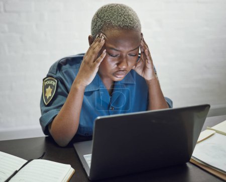 Photo for Police, woman with headache and working with stress on computer or frustrated with case, report or anxiety in security. African, officer and tired from work on documents in office or station. - Royalty Free Image