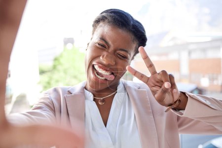 Foto de Mujer negra feliz, signo de paz y selfie en la ciudad con la lengua hacia fuera para la fotografía, memoria o vlog al aire libre. Rostro de una persona o empleado sonríe por diversión, humor o felicidad en una ciudad urbana. - Imagen libre de derechos