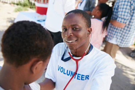 Photo for On a mission to provide great medical care. Shot of a volunteer doctor examining a young patient with a stethoscope at a charity event - Royalty Free Image