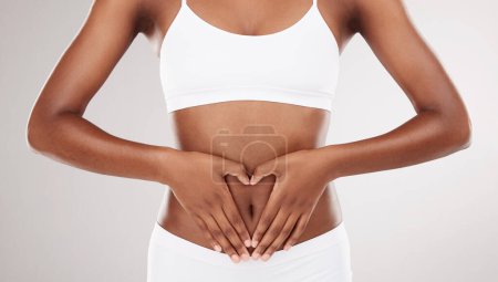 Heart shape, hands and stomach of a woman for health and wellness on a white studio background. Fitness, gut and diet of aesthetic female model for weight loss, balance or digestion and motivation.