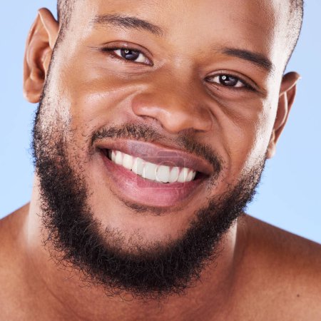 Photo for Cosmetics, closeup and black man with skincare, dermatology and grooming against a blue studio background. Male person, beard or model with treatment, face and glow with aesthetic, self care or smile. - Royalty Free Image