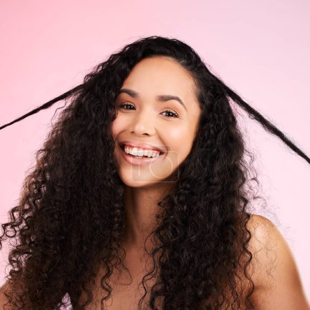 Photo for Face, woman and curly hair pull for beauty in studio isolated on a pink background. Portrait, natural cosmetics and hairstyle of happy model in salon treatment for growth, wellness and aesthetic. - Royalty Free Image