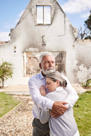 Photo for Couple, home in ruins after fire and hug at accident, disaster or crisis with hope and support with insurance. Property, senior man and woman hugging outside burned house, grief and real estate loss. - Royalty Free Image