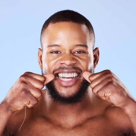 Photo for Portrait, black man and floss teeth in studio, healthy dental care or gum gingivitis. Face of male model cleaning mouth with oral thread for fresh breath, tooth cosmetics or plaque on blue background. - Royalty Free Image