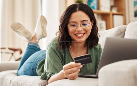 Photo for Relax, laptop and credit card, happy woman on sofa in living room for internet banking in home for online shopping. Ecommerce payment, smile and cashback, girl on couch with computer and website sale. - Royalty Free Image