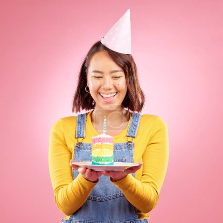 Foto de Vela de pastel de cumpleaños, estudio y feliz mujer asiática emocionada, sonreír y celebrar fiesta, regalo o regalo. Felicitaciones, wow y persona japonesa con postre, dulces o dulces sobre fondo rosa. - Imagen libre de derechos