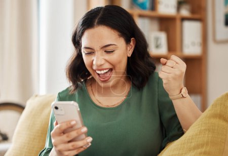Photo for Phone, winning and celebrate, happy woman on sofa with notification on bonus, deal or discount offer online. Win, social media and girl on couch with smile, cellphone and excited for surprise in home. - Royalty Free Image