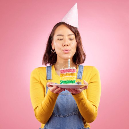 Photo for Birthday cake, studio and Asian woman blow candle, fire or flame for celebration party, present or event gift. Congratulations, wish and Japanese person with dessert, candy or food on pink background. - Royalty Free Image