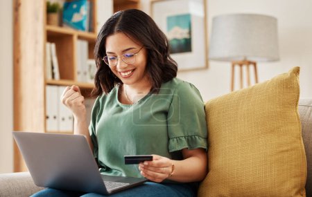 Photo for Winning, laptop and credit card, happy woman on sofa in living room for internet banking in home. Ecommerce payment, smile and cashback, girl at computer browsing retail website for online shopping - Royalty Free Image