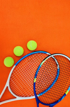Foto de ¿Quién quiere servir? Tiro de alto ángulo de elementos esenciales de tenis colocados sobre un fondo naranja dentro de un estudio - Imagen libre de derechos