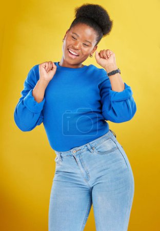 Foto de Feliz, danza y mujer joven en el estudio para la celebración, logro o meta con confianza. Felicidad, sonrisa y modelo femenino africano moviéndose a la música, canción o lista de reproducción aislado por el fondo amarillo - Imagen libre de derechos