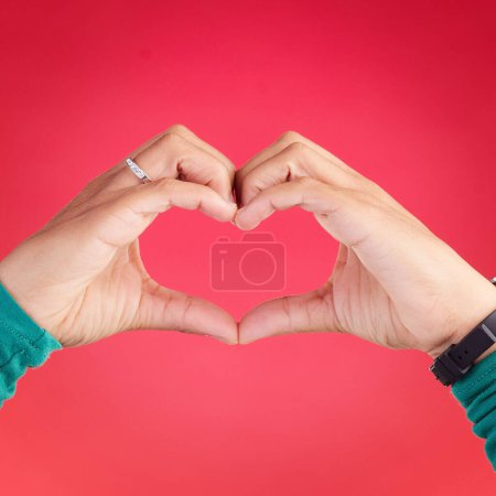 Téléchargez les photos : Gros plan, mains de personne et de cœur pour l'amour, le soin ou la compassion sur fond de studio rouge. Main dans l'amour emoji, forme ou symbole pour geste romantique, icône ou Saint-Valentin. - en image libre de droit