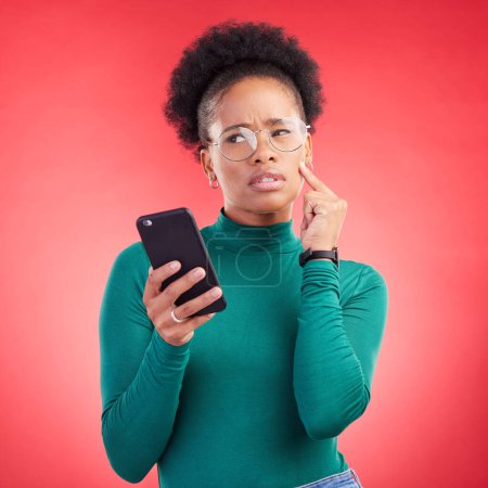 Photo for Thinking, phone and black woman in studio confused by text, application or how to steps on red background. Doubt, why and African person with questions for scam or spam contact on smartphone. - Royalty Free Image