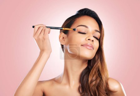 Photo for Makeup, eyeshadow and face of woman with brush on pink background for beauty, wellness and luxury. Cosmetology, aesthetic and female person with tools for foundation, cosmetics and glamour in studio. - Royalty Free Image