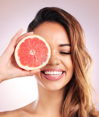 Photo for Citrus, grapefruit and face of woman with healthy, natural or organic beauty isolated in a brown studio background. Excited, eyes and young female person with vitamin c for skincare or detox. - Royalty Free Image