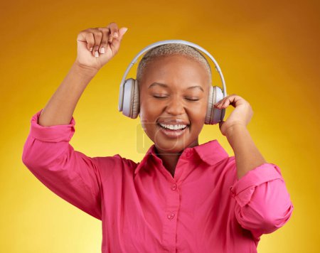 Téléchargez les photos : Écouteurs de musique, sourire et femme noire dansant en studio isolé sur fond jaune. Africain, heureux et à l'écoute de la radio, jazz ou streaming audio, podcast et entendre du son avec énergie. - en image libre de droit