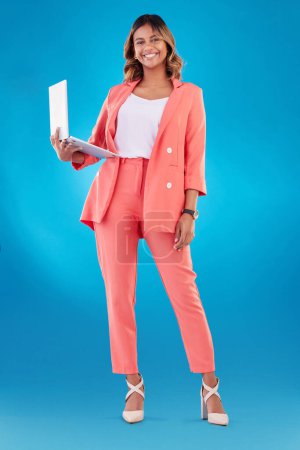 Photo for Computer, fashion and business woman for online marketing, social media planning or copywriting portrait in studio. E commerce, designer suit and full body of person on a laptop and blue background. - Royalty Free Image