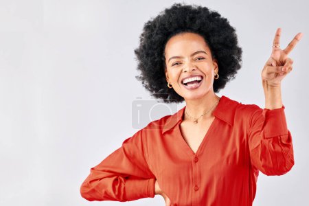 Foto de Loco, signo de paz y retrato de una mujer negra en un fondo de estudio con un emoji. Sonrisa, modelo divertida y una chica africana o empleado con un gesto de mano aislado en un telón de fondo para la comedia. - Imagen libre de derechos