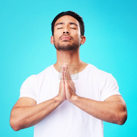Photo for Meditation, worship or man in prayer with hands and belief or faith in God for spirituality, mindfulness and peace in studio. Christian, praying and person with religion and zen on blue background. - Royalty Free Image